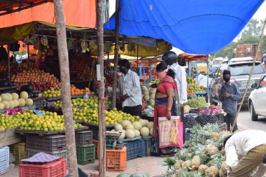 Hyderabad, Telangana, Hindistan. Temmuz-22-2020: Meyveler yol kenarında, meyve tüccarı yol kenarında meyve satarken koronavirüsten korunmak için maske takıyor, korona salgını zamanı, insanlar meyve alırken koruyucu maskeler takıyor
