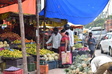 Hyderabad, Telangana, Hindistan. Temmuz-22-2020: Meyveler yol kenarında, meyve tüccarı yol kenarında meyve satarken koronavirüsten korunmak için maske takıyor, korona salgını zamanı, insanlar meyve alırken koruyucu maskeler takıyor