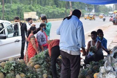 Hyderabad, Telangana, Hindistan. Temmuz-22-2020: Meyveler yol kenarında, meyve tüccarı yol kenarında meyve satarken koronavirüsten korunmak için maske takıyor, korona salgını zamanı, insanlar meyve alırken koruyucu maskeler takıyor