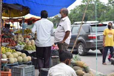 Hyderabad, Telangana, Hindistan. Temmuz-22-2020: Meyveler yol kenarında, meyve tüccarı yol kenarında meyve satarken koronavirüsten korunmak için maske takıyor, korona salgını zamanı, insanlar meyve alırken koruyucu maskeler takıyor