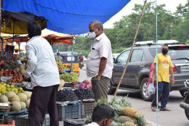 Hyderabad, Telangana, Hindistan. Temmuz-22-2020: Meyveler yol kenarında, meyve tüccarı yol kenarında meyve satarken koronavirüsten korunmak için maske takıyor, korona salgını zamanı, insanlar meyve alırken koruyucu maskeler takıyor