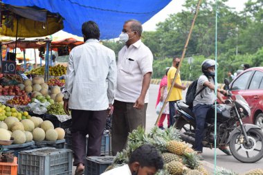 Hyderabad, Telangana, Hindistan. Temmuz-22-2020: Meyveler yol kenarında, meyve tüccarı yol kenarında meyve satarken koronavirüsten korunmak için maske takıyor, korona salgını zamanı, insanlar meyve alırken koruyucu maskeler takıyor