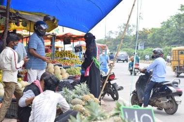 Hyderabad, Telangana, Hindistan. Temmuz-22-2020: Meyveler yol kenarında, meyve tüccarı yol kenarında meyve satarken koronavirüsten korunmak için maske takıyor, korona salgını zamanı, insanlar meyve alırken koruyucu maskeler takıyor