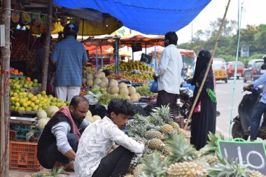Hyderabad, Telangana, Hindistan. Temmuz-22-2020: Meyveler yol kenarında, meyve tüccarı yol kenarında meyve satarken koronavirüsten korunmak için maske takıyor, korona salgını zamanı, insanlar meyve alırken koruyucu maskeler takıyor