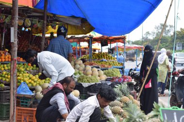 Hyderabad, Telangana, Hindistan. Temmuz-22-2020: Meyveler yol kenarında, meyve tüccarı yol kenarında meyve satarken koronavirüsten korunmak için maske takıyor, korona salgını zamanı, insanlar meyve alırken koruyucu maskeler takıyor