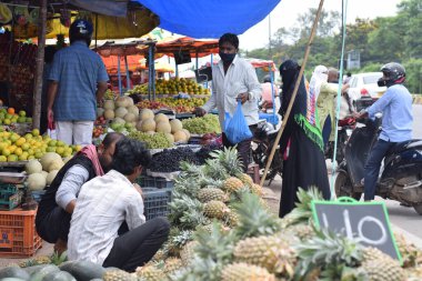 Hyderabad, Telangana, Hindistan. Temmuz-22-2020: Meyveler yol kenarında, meyve tüccarı yol kenarında meyve satarken koronavirüsten korunmak için maske takıyor, korona salgını zamanı, insanlar meyve alırken koruyucu maskeler takıyor