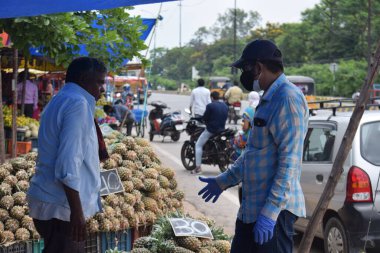 Hyderabad, Telangana, Hindistan. Temmuz-22-2020: Meyveler yol kenarında, meyve tüccarı yol kenarında meyve satarken koronavirüsten korunmak için maske takıyor, korona salgını zamanı, insanlar meyve alırken koruyucu maskeler takıyor