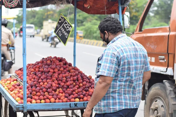 stock image Hyderabad, Telangana, India. july-22-2020: fruits at road side, fruits trader selling fruits at road side while wearing face mask for protection from the coronavirus, corona pandemic time, peoples are wearing protective masks while buying fruits