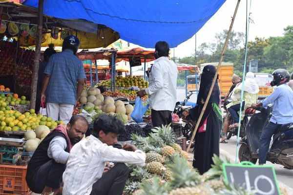 Hyderabad, Telangana, Hindistan. Temmuz-22-2020: Meyveler yol kenarında, meyve tüccarı yol kenarında meyve satarken koronavirüsten korunmak için maske takıyor, korona salgını zamanı, insanlar meyve alırken koruyucu maskeler takıyor