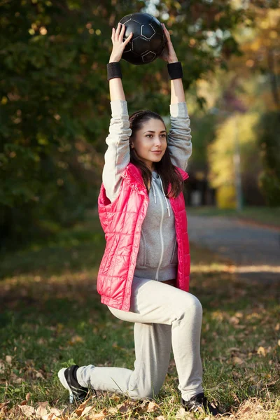 Young woman doing squats with ball