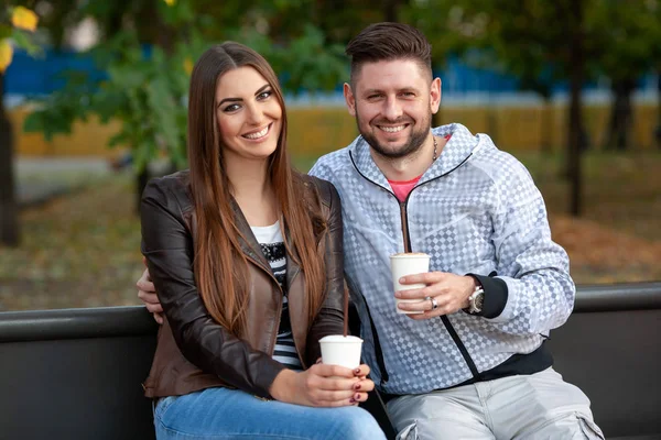 快乐的现代情侣在公园里喝咖啡 看摄像机 — 图库照片