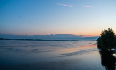 Sakin bir nehrin üzerinde resim gibi gün doğumu.