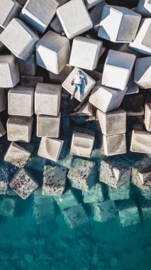 İspanya 'nın Malaga limanındaki dalgalardan kıyıları koruyan beton bloklardaki genç bir adamın hava görüntüsü..