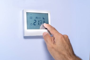 Sıcaklığı ayarlayan bir termostatın dokunmatik ekranına elle bastır