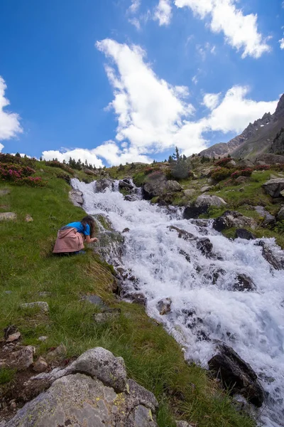 girl drinking water from a mountain river in the spanish pyrenees vertical