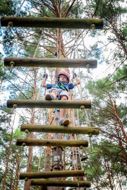 Tibet Köprüsü 'nden geçen bir çocuk aşağıdan bir çam ormanı manzaralı bir macera parkında