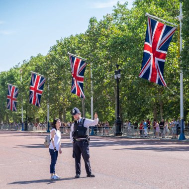 Londralı polis Londra Buckingham Sarayı 'ndaki Asyalı turiste bilgi veriyor.