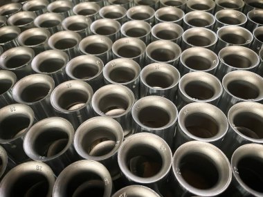 Alüminyum silindirik tüpleri düzenli bir şekilde tekrar eden bir kalıba dökerek ölürler. Metalik yüzeyler ışığı yansıtarak dokulu ve endüstriyel bir estetik oluştururlar. Die oyuncu seçimi, seri üretim.