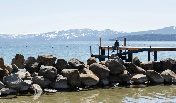 Orang Duduk Ujung Pier Atas Danau Dikelilingi Oleh Pegunungan — Stok Foto