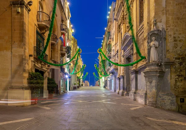 The main city street of the Republic in the light of lanterns at dawn. Valletta. — Stock Photo, Image