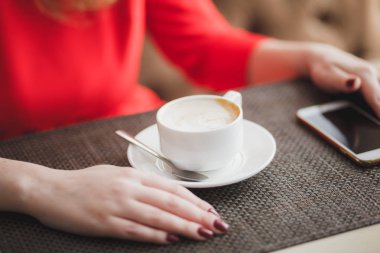 Elinle masaya bir fincan kahve koy.