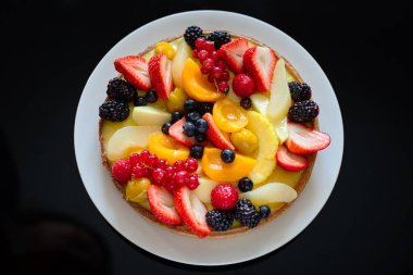 Siyah arka planda taze meyveli kek.