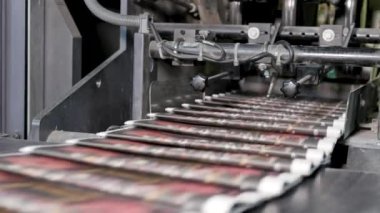 Basılı gazeteler baskı fabrikasında yüksek hızda taşıyıcıda hareket ediyor.