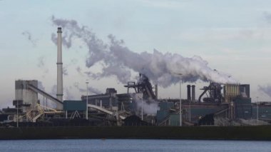 Güneşli bir akşamda bacaları tüten Tata Çelik Fabrikası, IJmuiden, Hollanda