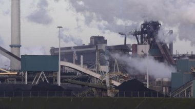 Güneşli bir akşamda bacaları tüten Tata Çelik Fabrikası, IJmuiden, Hollanda