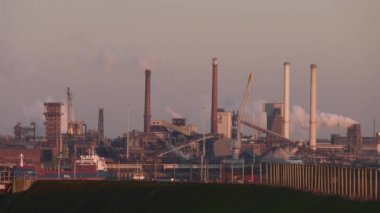 Güneşli bir akşamda bacaları tüten Tata Çelik Fabrikası, IJmuiden, Hollanda