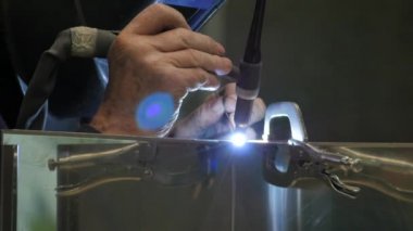 Metal parçaları kaynaştıran işçilerin yakın çekim görüntüleri.