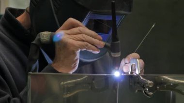 Metal parçaları kaynaştıran işçilerin yakın çekim görüntüleri.