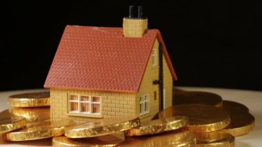 Oyuncak ev, siyah arka planda dönen Euro parasıyla çevrili.