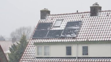 Bir evin çatısındaki güneş panellerine kar yağıyor.