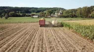 Belçika 'da mısır hasat eden traktör ve traktörün havası.
