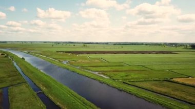 Hollanda çayırlarındaki kümülüs bulutlu geleneksel yel değirmeninin 4K 'lık hava görüntüsü.