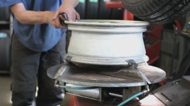 Garajda lastik montajı yapan bir makine var. Arabanın kenarı temizleniyor.