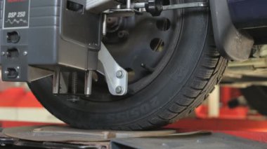 Araç tekerleği bilgisayarlı tekerlek hizalama makinesiyle sabitlendi. Direksiyon hareketli bir lastiği yakından çek.