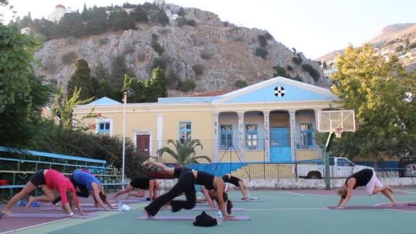 晴れたギリシャの風景の中でヨガを練習している人々のグループの映像 — ストック動画