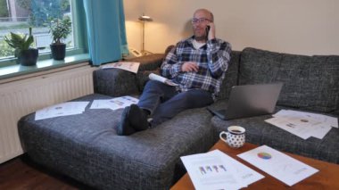 Evde dizüstü bilgisayarla çalışan yetişkin bir adamın görüntüleri.