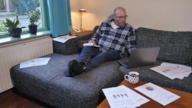 Evde dizüstü bilgisayarla çalışan yetişkin bir adamın görüntüleri.