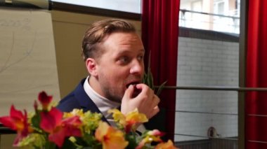 Yakışıklı yetişkin iş adamının ofiste şeker yerken çekilmiş görüntüleri.