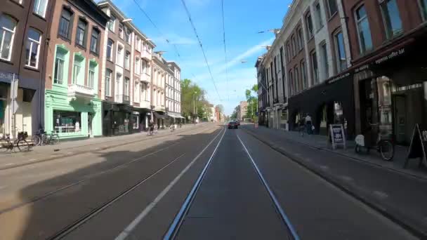 AMSTERDAM, NIZOZEMSKO - 8. května 2020: POV projíždí opuštěnými ulicemi a Beurs van Berlage v Amsterdamu během krize korony