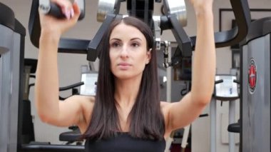 Güzel esmer bir kadının spor salonunda spor yaparken çekilmiş görüntüleri.