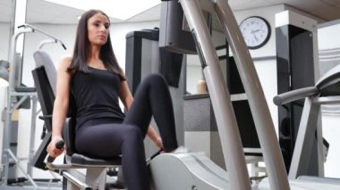 Güzel esmer bir kadının spor salonunda spor yaparken çekilmiş görüntüleri.