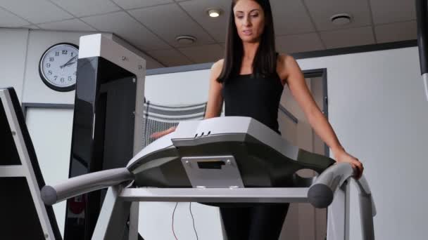 在跑步机上在健身房锻炼的漂亮的黑发女人的镜头 — 图库视频影像