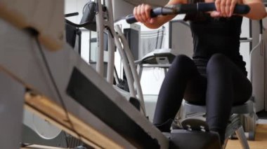 Güzel esmer bir kadının kürek makinesinde spor yaparken çekilmiş görüntüleri.