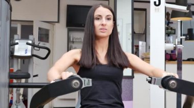 Güzel esmer bir kadının spor salonunda spor yaparken çekilmiş görüntüleri.