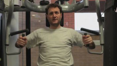 Spor salonunda ağırlık kaldıran yakışıklı bir genç.