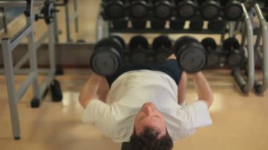 Spor salonunda ağırlık kaldıran yakışıklı bir genç.